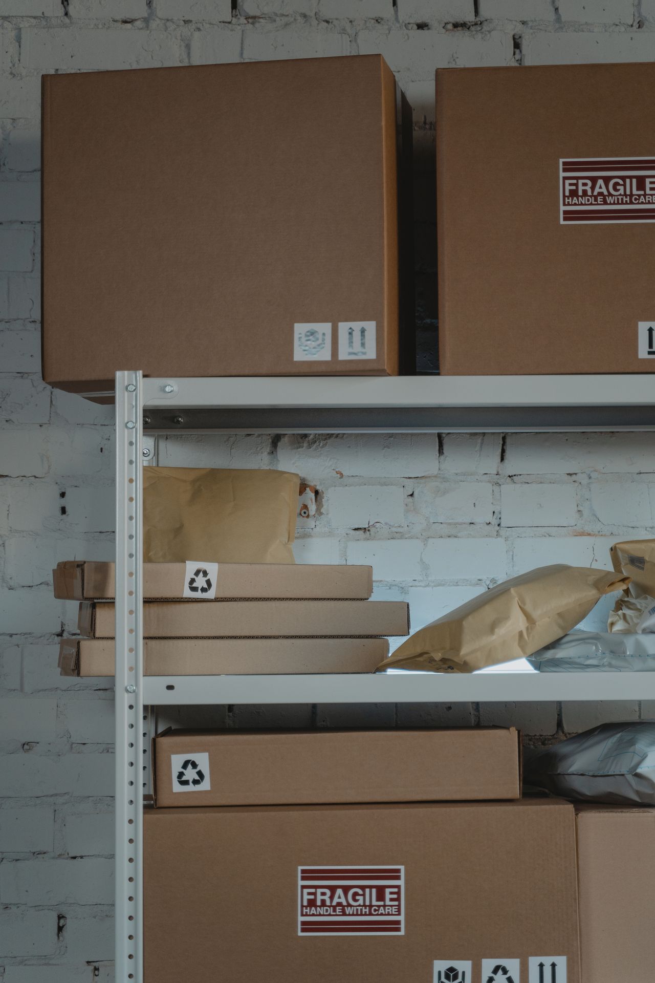 Cardboard boxes and padded envelopes on a steel shelf.