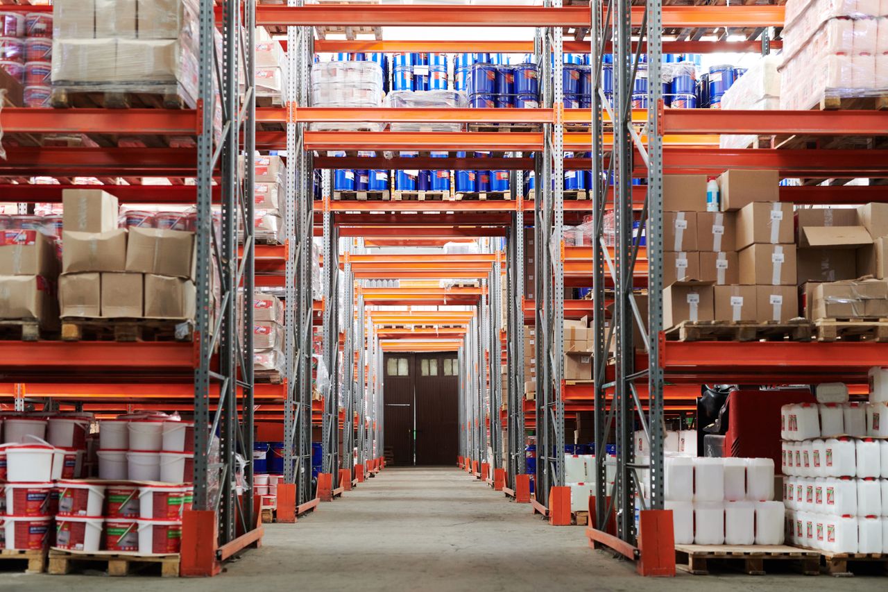 An aisle between high shelves stacked with pallets and cartons.